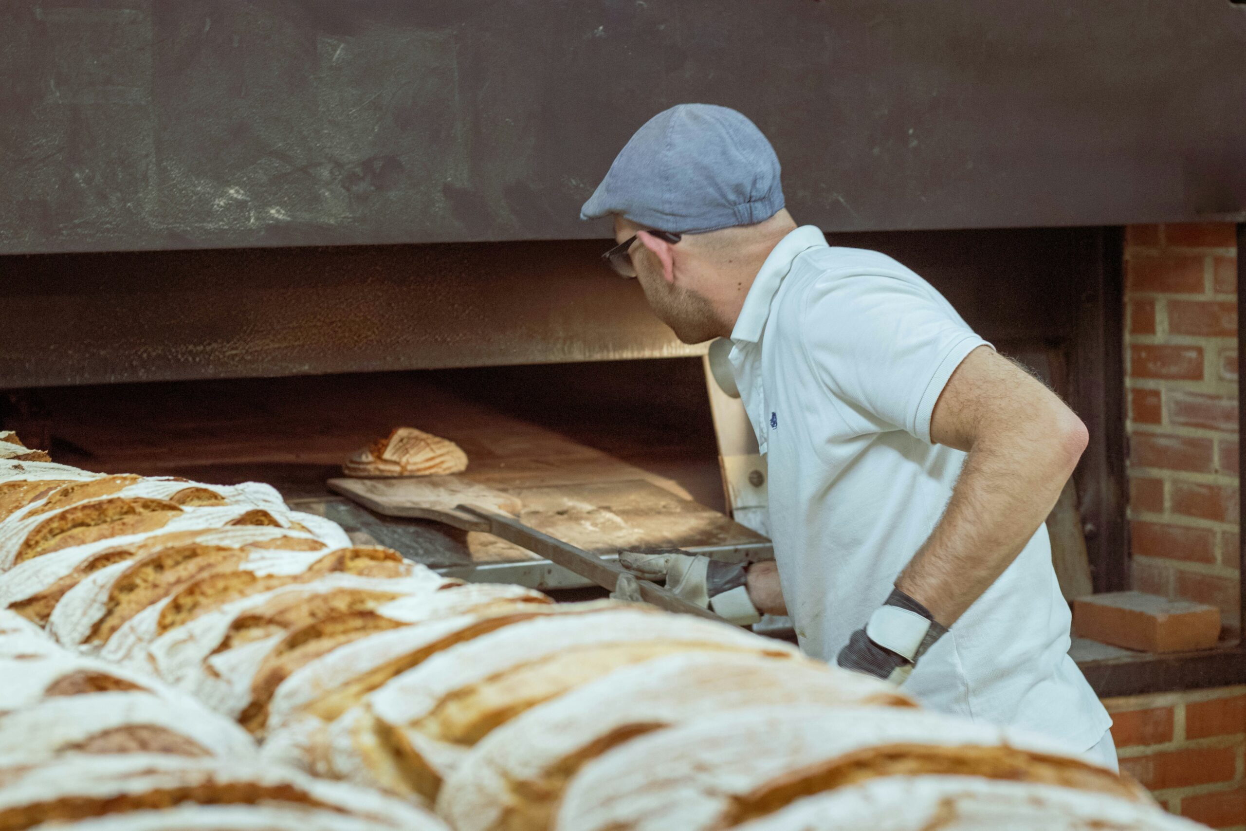 Mann schiebt Brotlaibe in Ofen