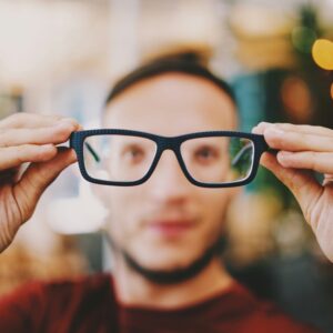junger Mann bekommt Brille aufgesetzt